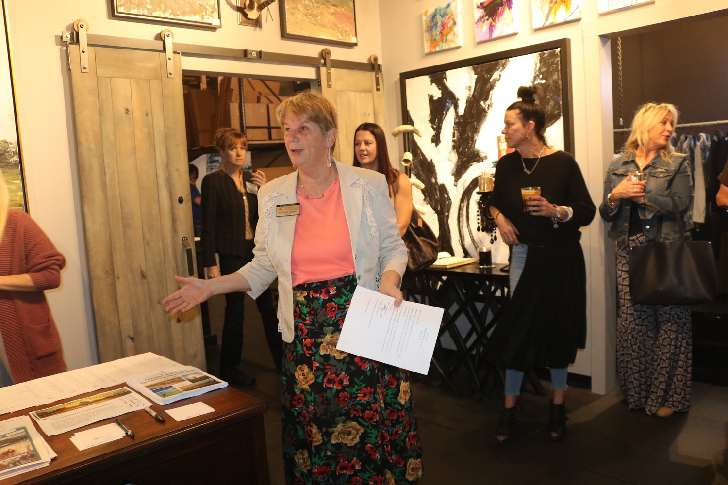 Kathleen Floryan is surrounded by artwork as she speaks to those in attendance during the “After Hours” event hosted by John Beard Art Gallery.